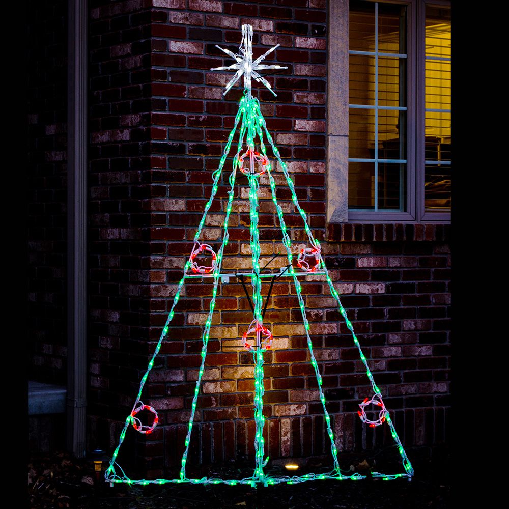 Christmas Tree with Berries LED display installed near exterior brick wall at night, green LED outline with red berry accents and lighted star topper

